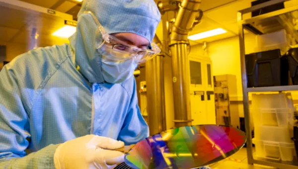 A researcher in a cleanroom suit with a 200mm wafer in the nanofabrication cleanroom