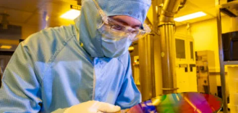 A researcher in a cleanroom suit with a 200mm wafer in the nanofabrication cleanroom