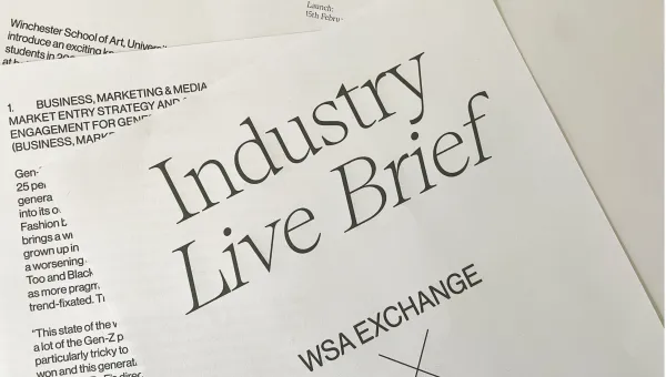 A report is printed on white paper and the pages are scattered, overlapping each other. The top page has the text 'Industry Live Brief. WSA Exchange X Fendi.