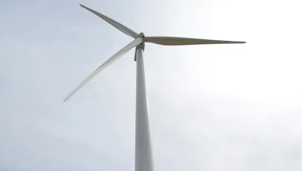 Wind turbine under cloudy sky.
