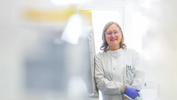Scientist smiling next to lab equipment