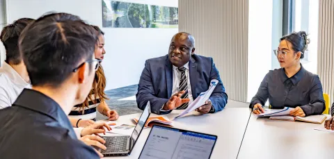 Professor Ven Tauringana and students dicussing at table