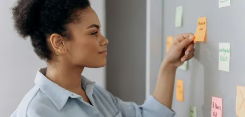 A woman at a whiteboard adding post-it notes