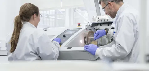 2 researchers placing samples in a scintillation counter.
