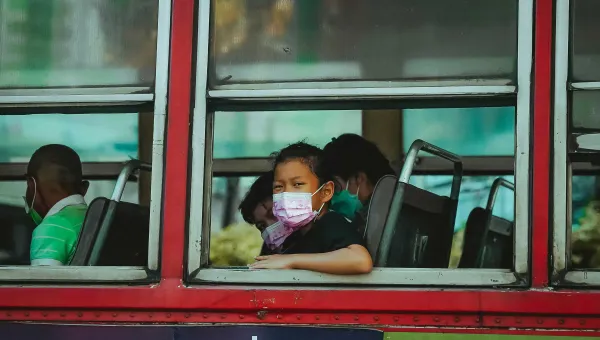 Girl with mask sitting inside bus