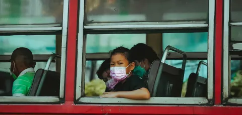 Girl with mask sitting inside bus