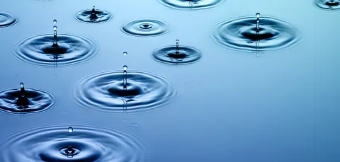 Droplets of water falling on water along with their concentric wave patterns