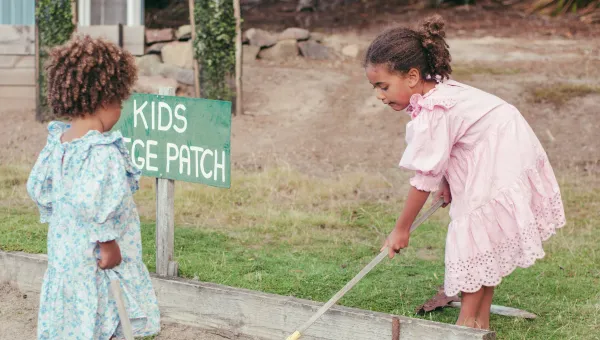 Two children gardening at a kids' veggie patch.