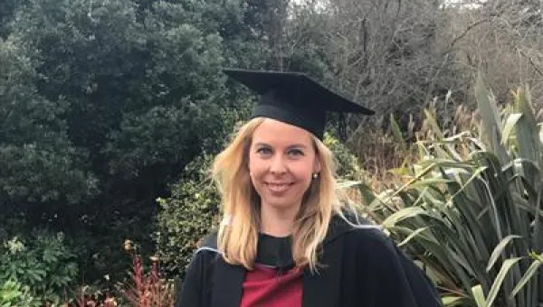 Dr Jess Jarvis smiles at the camera in her graduation gown and cap