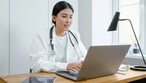 A doctor sits at a laptop doing research