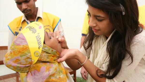 Woman giving a child a polio vaccination