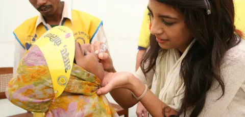 Woman giving a child a polio vaccination
