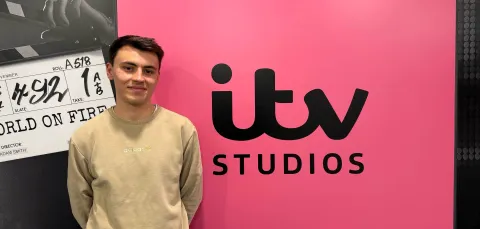 BA Spanish and Linguistics Graduate, Joe Dobinson standing by a sign for ITV studios.