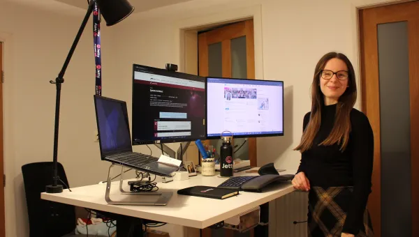 Elizabeth Gardiner standing for a photo next to a dual monitor computer set-up.