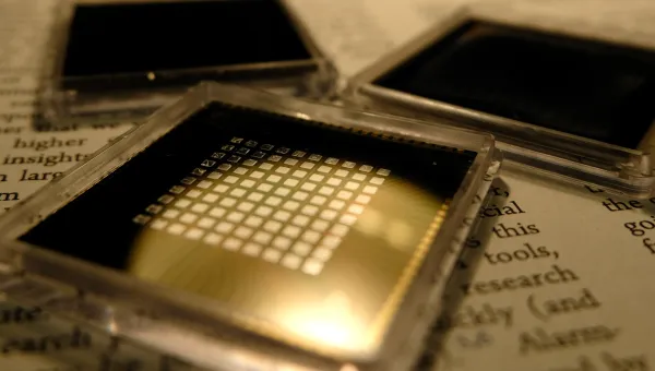 three small square microchips placed on the pages of a book with visible text.