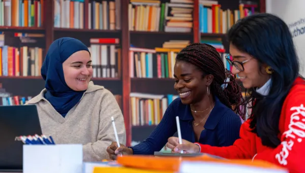 Students working together using digital tablets in a library-style setting.