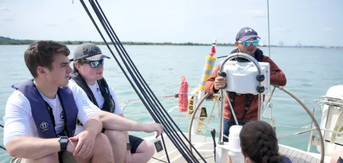 Students sitting on a boat, watching an instructor.