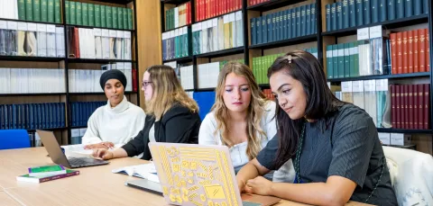 Students sat at table in library