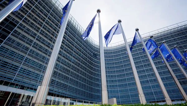 European parliament building with EU flags flying outside.