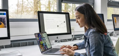 A student working on a laptop in the Wimnchester school of art fashion design studio