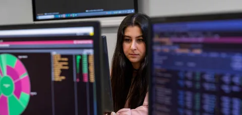 A student is surrounded by Bloomberg terminals, showing data in various colourful representations. 