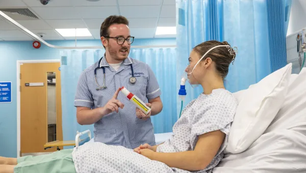 Student nurse helping patient with breathing equipment