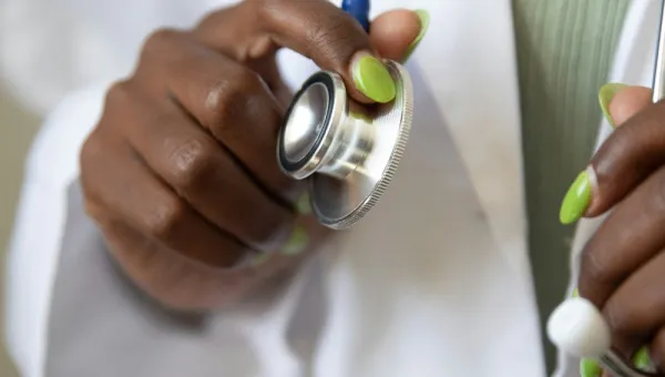 A healthcare student with a clean white lab coat readies their stethoscope
