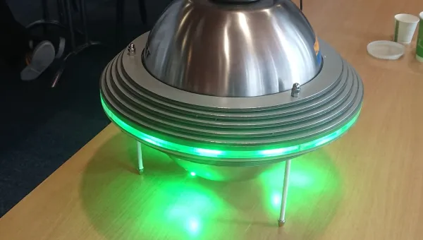 Device placed on a table, glowing green.