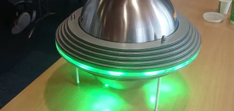Device placed on a table, glowing green.