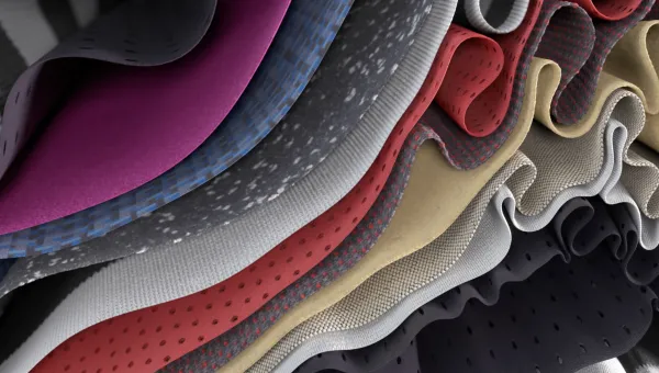 A close-up view of layered, folded fabrics in different colours and textures, shown in a wavy, rippled arrangement.