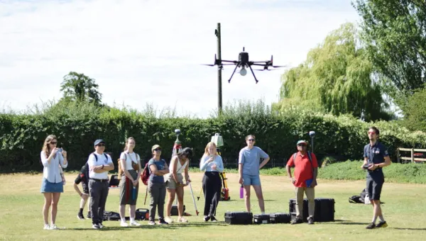 A group of people out on a field using an aerial drone.