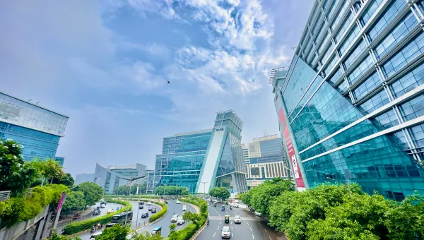 Modern glass office buildings and busy road in Gurgaon, India.