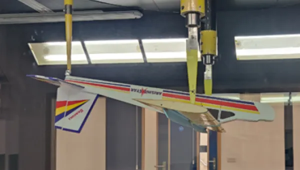 An upside‑down model aeroplane with colourful stripes is suspended from the ceiling inside a wind tunnel at the University of Southampton.
