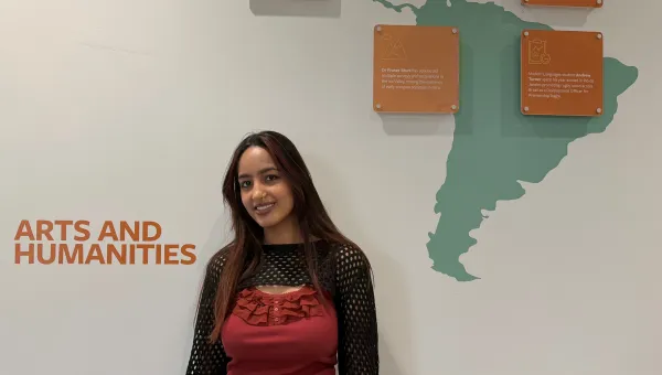 BA History student standing in front of a wall map of South America.