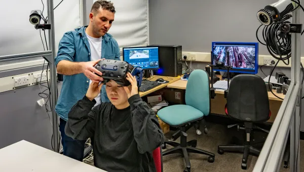 Two researchers placing visor on one of them