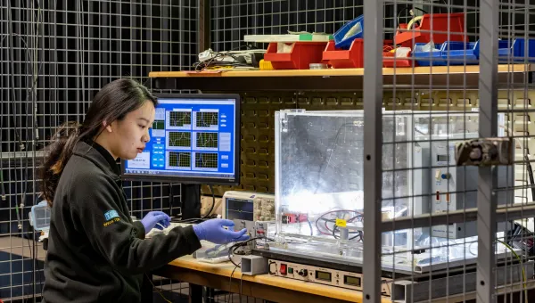 Researcher conducting electrical testing and monitoring data on laboratory equipment in a controlled test environment