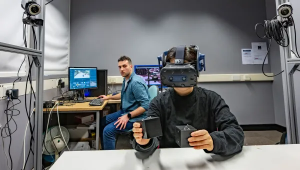 Researchers sitting down at a computer and one with a visor on