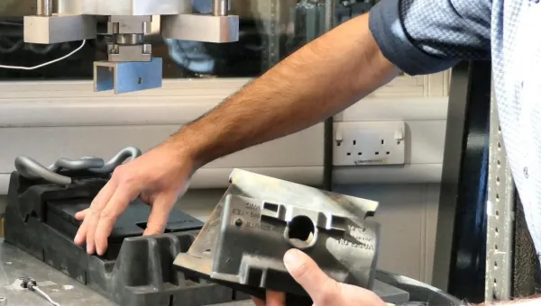 Researcher preparing a component for testing in a laboratory materials testing machine