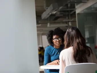 Adviser and student talking at a small table.