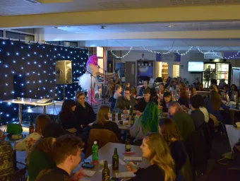 Lots of students sat at tables watching a drag queen on stage. 