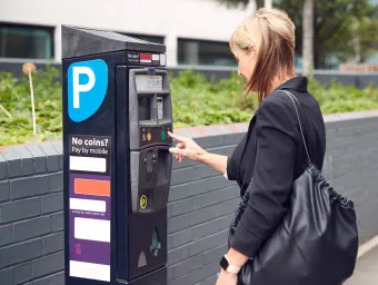 Visitor paying for car park at a parking machine. 