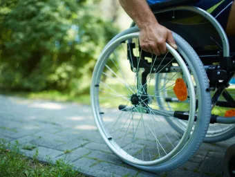 Close up of wheel on wheelchair on a sunny outdoor path. 