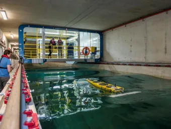 Three students test a model boat in the towing tank