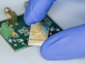 Two fingers wearing globes holding a microchip