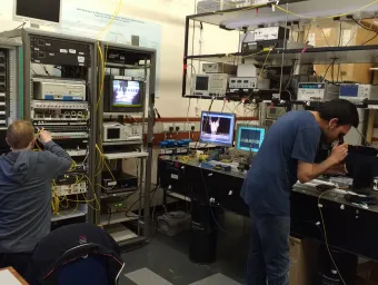 Two researchers from the optical fibre communications group at work against a backdrop of complex equipment 