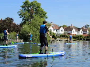 A group of young people paddleboarding on a river on a sunny day
