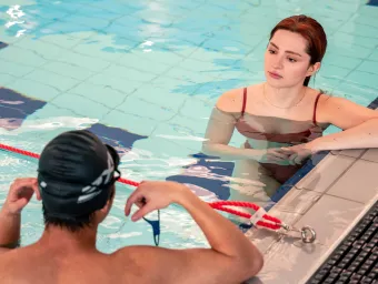 2 swimmers leaning on the edge of a pool talking