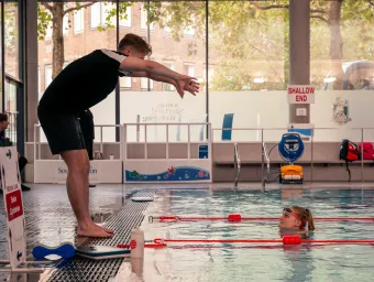 An instructor demonstrating a stroke to a student in the pool