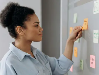 A woman at a whiteboard adding post-it notes