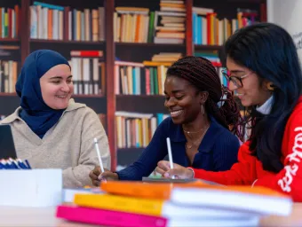Students working together using digital tablets in a library-style setting.